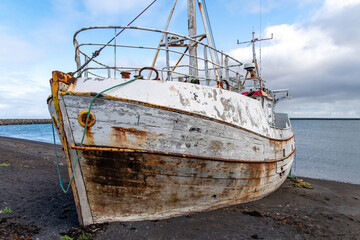 Front bow view of a beached, shipwrecked, abandoned fishing boat on the black sand beach near Utnesvegur on the western side of Iceland from the port of Sandgerdi