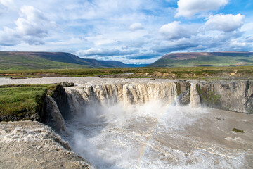 Fototapeta na wymiar Panoramic view from the Eastern bank of the Godafoss waterfall in Iceland which runs through the Bardardalur valley: light rainbow visible