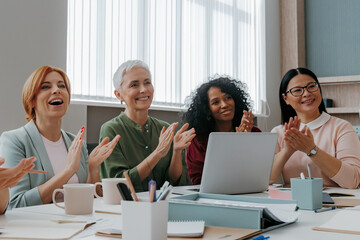 Group of happy businesswomen applauding while having meeting in the office - 749385036