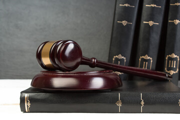 Law concept - Open law book with a wooden judges gavel on table in a courtroom or law enforcement...