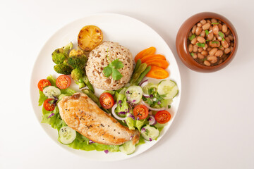 Grilled chicken in a plate with salad and rice isolated clean white background top view photo