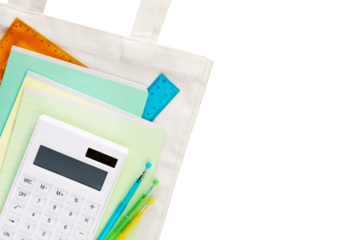Back to school flat lay. Isolated multi colored notebooks, pens, rulers and calculator on a white textile bag. School supplies on transparent background with copy space. School sale and buying concept