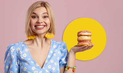 Happy young woman holding doughnuts and smiling against pink background - 749418835