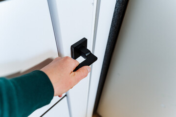 Using a sleek black handle, the person opens the door with a smooth gesture