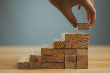 Hand arranging wood block stacking as step stair. Ladder career path concept for business growth...