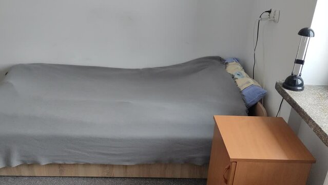 Bed in a small cozy student room in a student dormitory