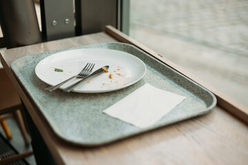 lunch tray with Empty dirty dish. White plate with fork and knife on table after dinner