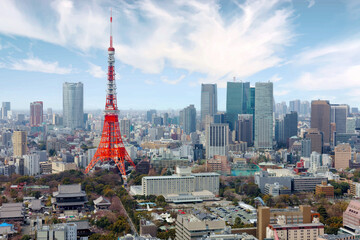 Beautiful city skyline of Downtown Tokyo, with the famous Tokyo Tower standing tall among modern skyscrapers under blue sunny sky & Zoujou-ji Buddhist Temple near the base of the eye-catching landmark