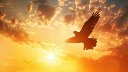 Obraz premium The silhouette of a crow flying at dawn, with its wings spread wide against a cloudy golden sunrise sky.