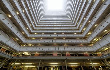 Low angle diminishing perspective view from the atrium of a multistorey public housing in Hong Kong, with sunlight cast from the top and the multilayers of corridors making a unique geometric pattern