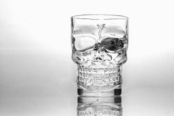 Um copo de vidro em formato de crânio com água em um fundo branco