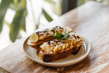Toast with peanut butter and fruit. Delicious snack on a wooden table