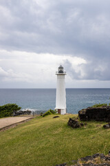 Fototapeta na wymiar Le Phare du Vieux-Fort, white lighthouse on a cliff. Dramatic clouds overlooking the sea. Pure Caribbean on Guadeloupe, French Antilles, France