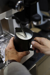 barman calentando leche en la maquina de expreso para hacer cafés con leche