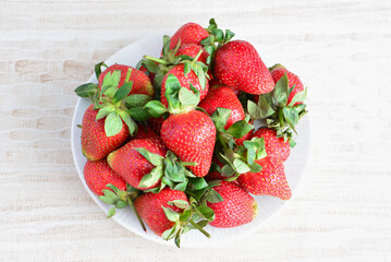 plate with fresh garden strawberries isolated top view 