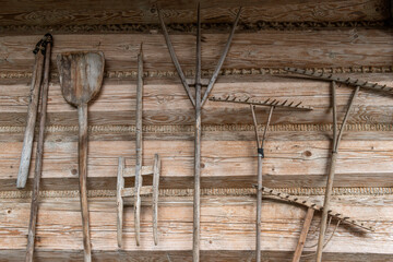 Drewniane narzędzia rolnicze na tle ściany wiejskiej drewnianej chaty - obrazy, fototapety, plakaty