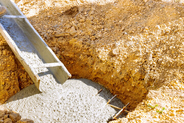 Foundation worker pouring ready mix cement concrete for building in construction site