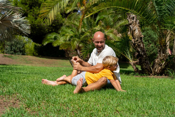 funny father playing with baby feet. . laughter therapy. father tickles his son's legs