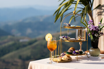 Luxury afternoon tea set presented on a tiered stand with a refreshing drink of iced lemon tea and...
