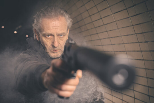 Old member of criminal  gang armed with handgun shooting in gun smoke