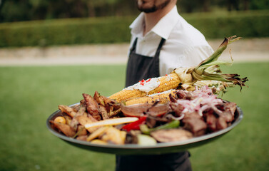 The waiter offers cold snacks, canapés. Catering, service, aperitif. Celebration, event under the open sky outside