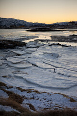 Frozen sea, with yellow hue of winter sun, Sommaroy near Tromso, northern Norway
