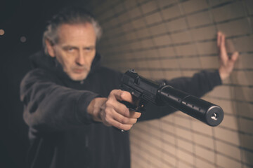 Old member of criminal  gang armed with handgun in dark tunnel - obrazy, fototapety, plakaty