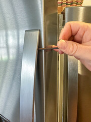 Using an Allen wrench to tighten the handle on a refrigerator 