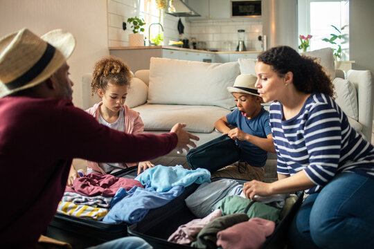 Family packing suitcase together for vacation in living room