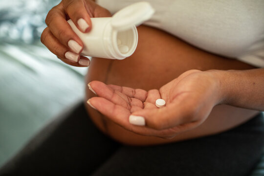 Pregnant woman taking vitamin pills at home