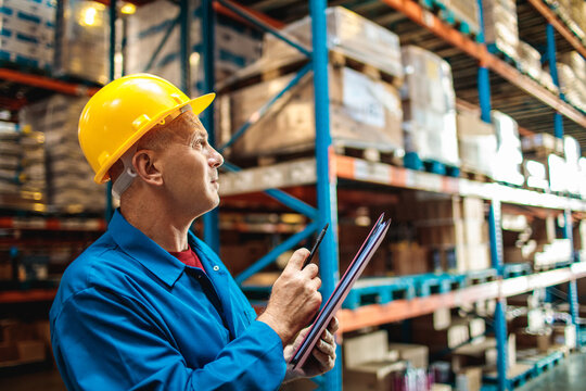Mature warehouse manager with clipboard checking inventory