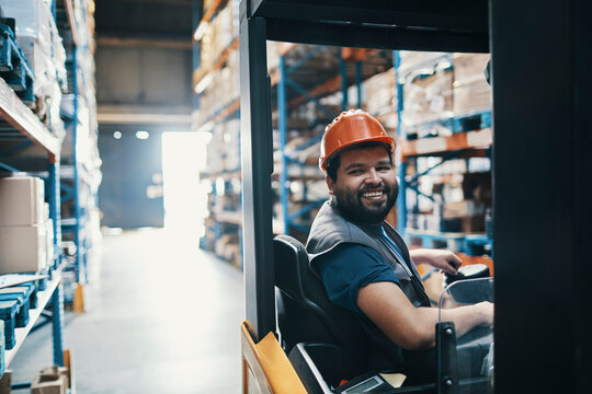 Smiling male forklift operator working in warehouse