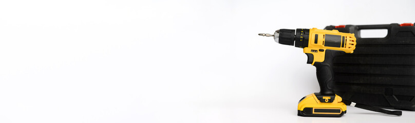 Fototapeta premium Banner, electric cordless yellow drill screwdriver and black carrying case on a white background. Concept of construction, repair, electrical equipment, modern tools. Copy space. Advertising space