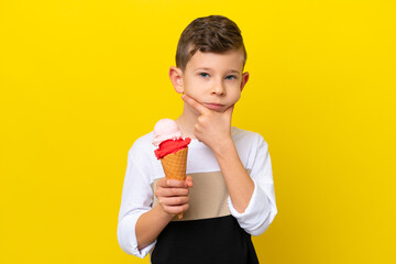 Little caucasian boy with a cornet ice cream isolated on yellow background thinking