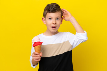 Little caucasian boy with a cornet ice cream isolated on yellow background with surprise expression