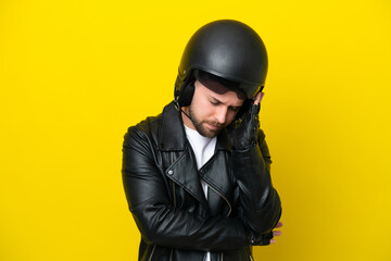 Young caucasian man with a motorcycle helmet isolated on yellow background with headache