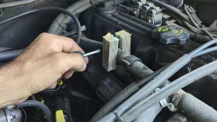 Repairing a pipe on a vehicle using makeshift tools - two planks and two screws adjustable with a screwdriver. Emergency repair in extreme conditions without additional costs