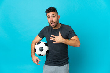 Football player isolated on blue background surprised and shocked while looking right