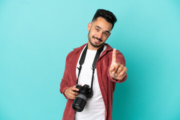 Young photographer caucasian man isolated on blue background showing and lifting a finger