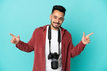 Fototapeta premium Young photographer caucasian man isolated on blue background pointing finger to the laterals and happy