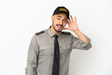 Young security  caucasian man isolated on white background listening to something by putting hand on the ear