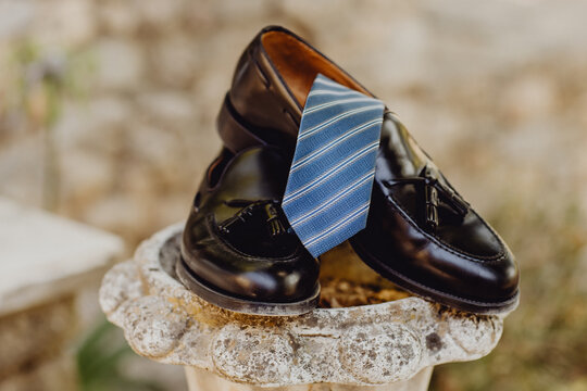 Chaussures en cuir noires et cravate bleue &agrave; rayures