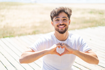 Handsome Arab man at outdoors With glasses making heart with hands