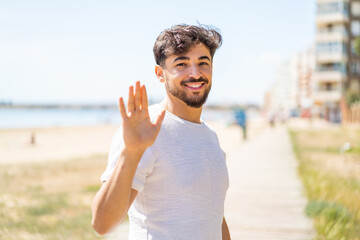 Handsome Arab man at outdoors saluting with hand with happy expression