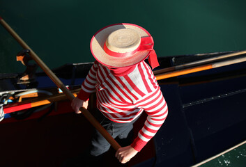 Venetian gondolier with the red and white striped shirt while rowing the Gondola in the Grand Canal - obrazy, fototapety, plakaty