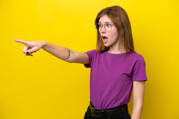 Young English woman isolated on yellow background pointing away