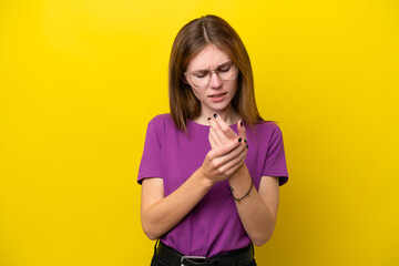 Young English woman isolated on yellow background suffering from pain in hands