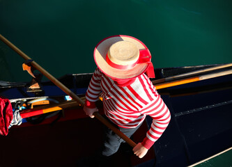 gondolier with white and red hat rowing on gondola on grand canal in Venice in Italy in Europe - obrazy, fototapety, plakaty
