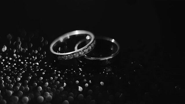 Two beautiful silver rings lie on a black background and are illuminated by an interesting light
