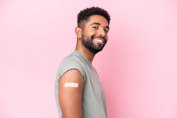 Young Brazilian man wearing a band aid isolated on pink background with happy expression